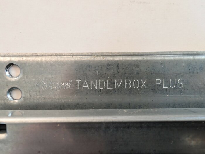 Metallskena med texten "blum TANDEMBOX PLUS" ingraverad.