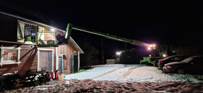 Teleskoplastare används för att lasta saker på ovanvåning på ett snötäckt hus vid natt.