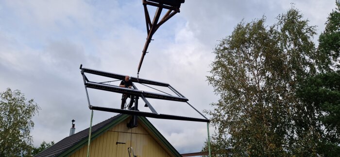 Man installerar vridbar ställning för solfångare på taket av ett hus med hjälp av en teleskoplastare.