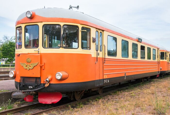 Orange och vit rälsbuss står på en järnvägsstation.