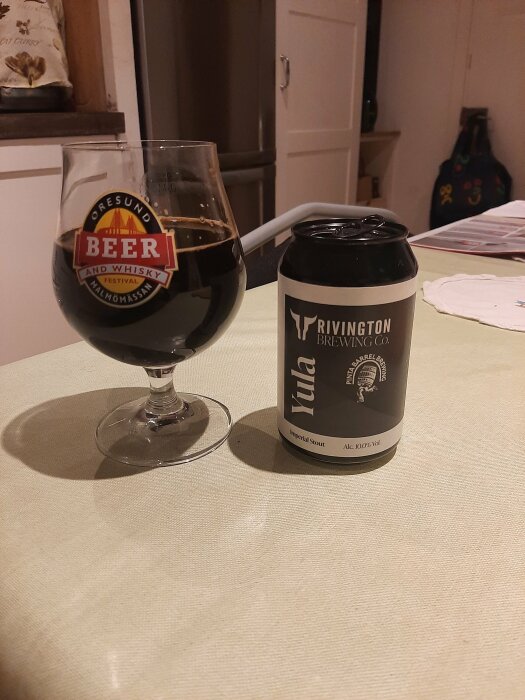 Glas med öl bredvid en burk Rivington Brewing Co. Yula Imperial Stout på ett köksbord.