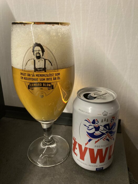 Ett fullt glas öl bredvid en burk med Zywiec-märke.