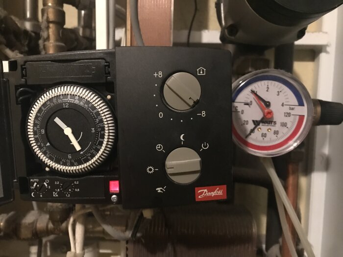 Närbild av en Danfoss fjärrvärmeregulator med vred inställt på -8, och en tryckmätare som visar strax under 40 grader Celsius.