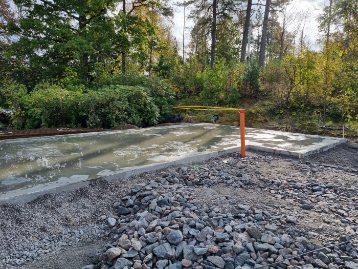 Nylagd garageplatta i betong omgiven av grus och natur, del av källarprojektets återfyllnad.