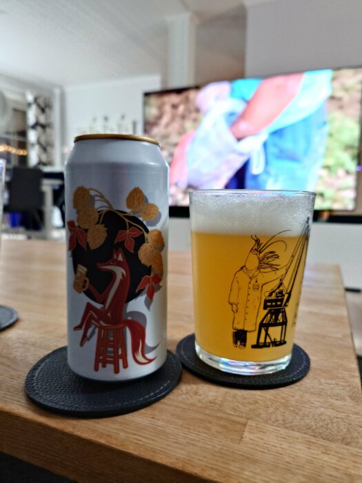 Ölburk och glas med gul dryck på ett bord, burken dekorerad med en räv som sitter på en pall, TV i bakgrunden.