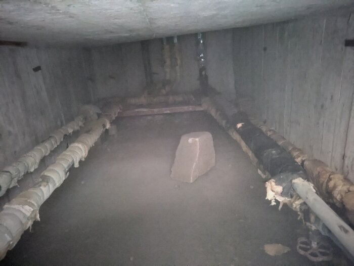 Gamla rör och skjutventiler i en trång betongkällare, där ventilerna inte längre fungerar korrekt.