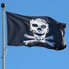 Svart piratflagga med dödskalle och korslagda benknotor vajar mot blå himmel.