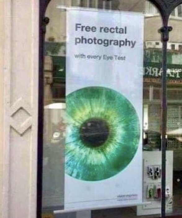 Skyltfönster med affisch: "Free rectal photography with every Eye Test" och en stor bild på en iris.