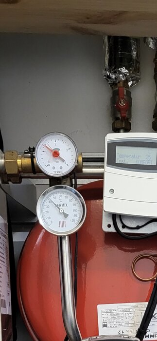 Manometer och termometer på ett radiatorsystem med digital display som visar temperaturinställning.