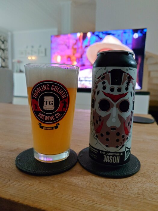 Ett glas öl med texten "Toppling Goliath Brewing Co." och en burk öl med en mask-illustration, matchad med "Jason Bra" från Funky Fluid.