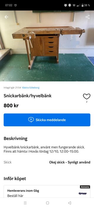 Hyvelbänk med skruvstycke och lådor, placerad mot en vit vägg. Grönmålat golv syns under bänken.