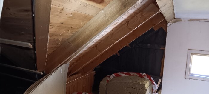 Snedtak i vind med träpaneler och isoleringsmaterial.