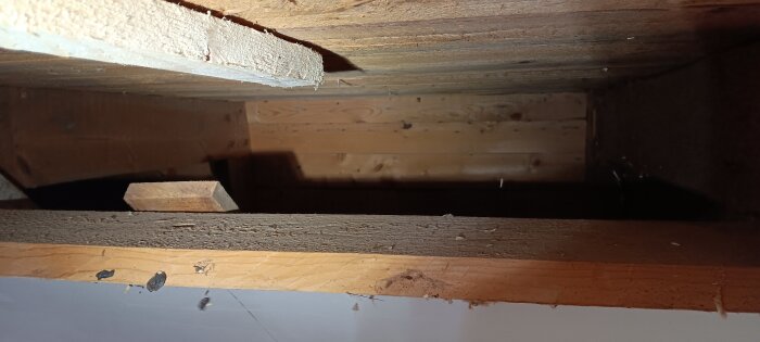 Insida av kattvind med träpanel och kutterspån i takfoten, sett i samband med isolering och ventilation.