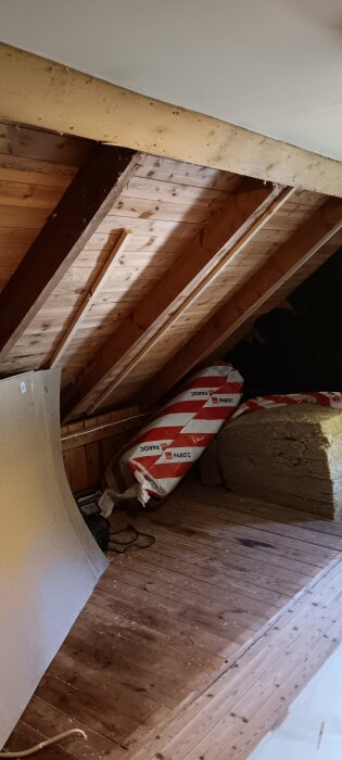 Kattvind med träpanel, isolering och verktyg; material märkt Paroc.