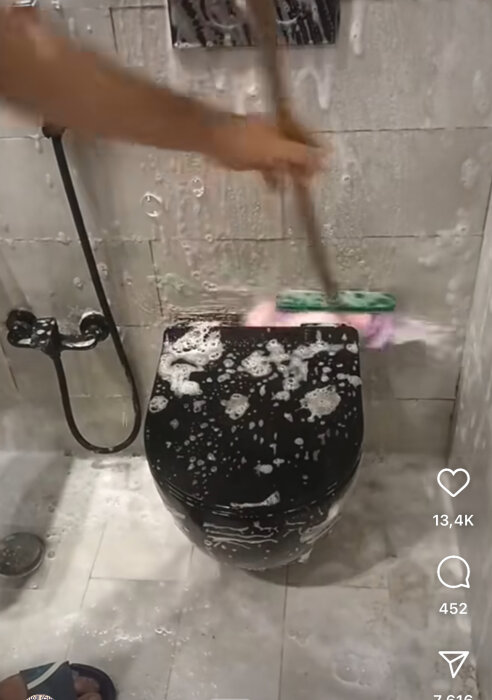 En person rengör en toalett med en borste fylld av skum.