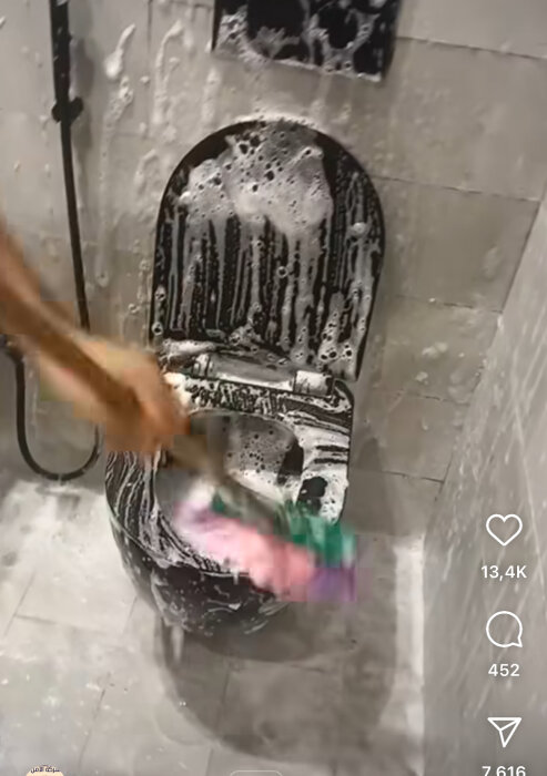 Person skurar en toalettstol täckt av skum med en borste.