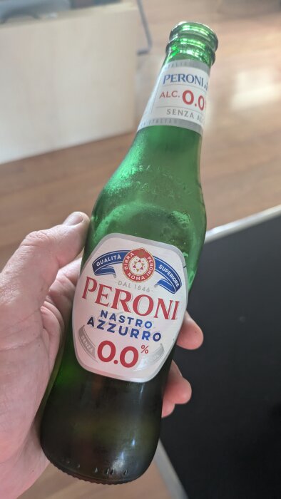 Person håller en flaska alkoholfritt Peroni Nastro Azzurro-öl efter löprunda.