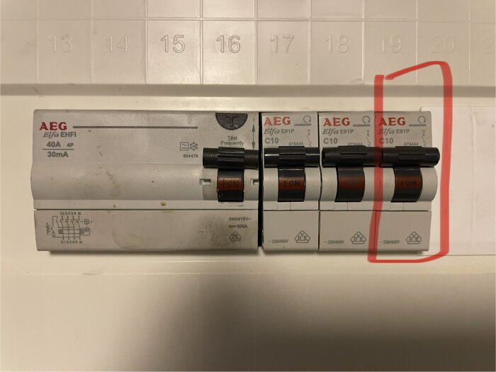 Närbild på en grupp central med säkringar av märket AEG, varav en säkring har löst ut och markerats med en röd cirkel.