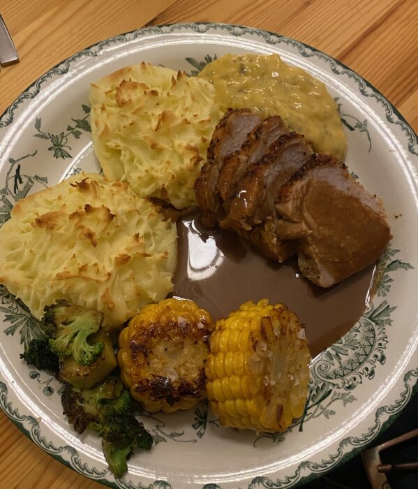 Tallrik med pommes duchesse, helstekt kotlettrad med madeirasås, bearnaisesås, grillad majs och broccoli.