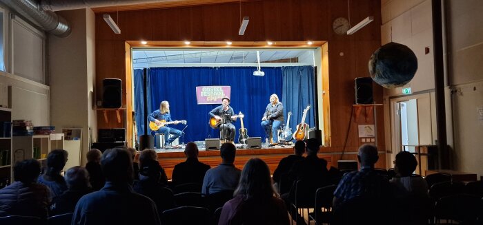 En liten scen med tre musiker som spelar akustisk gitarr och sjunger inför en sittande publik, på en gospel-festival.