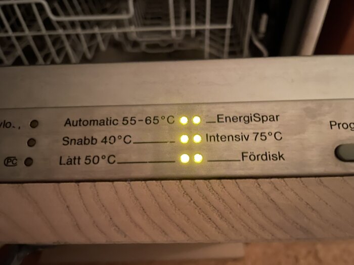 Närbild av diskmaskinskontrollpanel med lampor som lyser för "Energispar," "Intensiv 75°C," och "Automatisk 55-65°C.