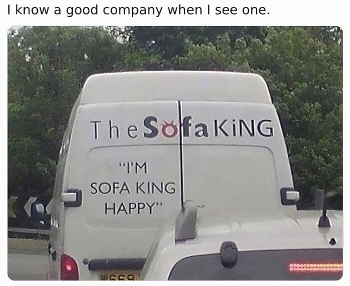 Bakdelen av en vit skåpbil med texten "The Sofa King" och "I'm Sofa King Happy" målad på.