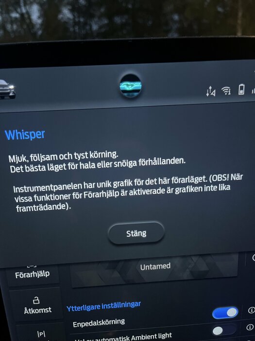 Bilden visar en bilskärm med text om körläget "Whisper" för hala vägförhållanden, med grafik ovanför och knappen "Stäng".