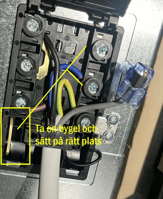 En elkopplingsbox med kablar och instruktion om att sätta en bygel på rätt plats.