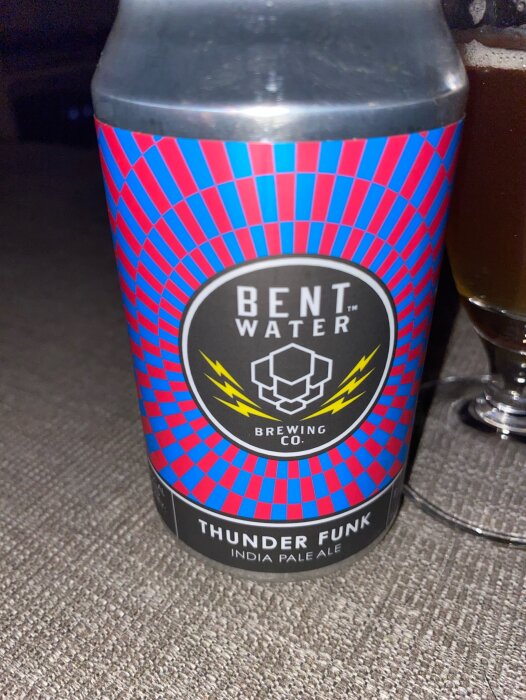 Ölburk med etiketten "Thunder Funk" från Bent Water Brewing Company, med ett färgstarkt, geometriskt mönster i rött och blått.