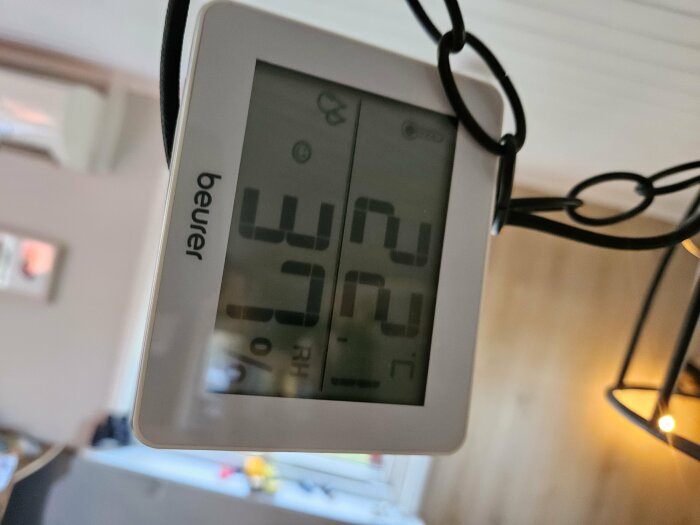 Hygrometer med digital display visar 22 grader Celsius och 37% luftfuktighet i vardagsrum.