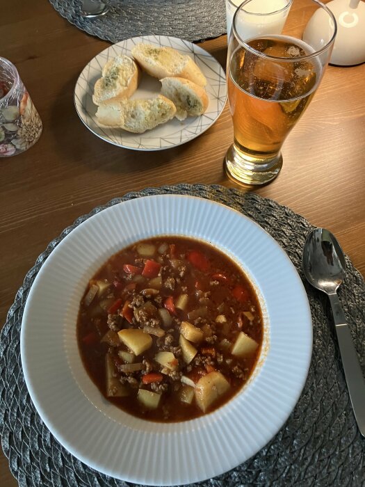 Tacosoppa serverad med vitlöksbröd på en tallrik, öl i ett glas bredvid.