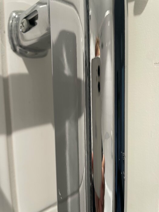 Närbild på en kromad handdukstork monterad mycket nära ett dörrfoder, vilket visar installationsutmaningen.