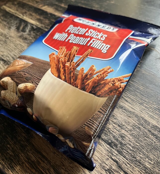 Förpackning med pretzelsticks fyllda med jordnötssmör på ett träbord.