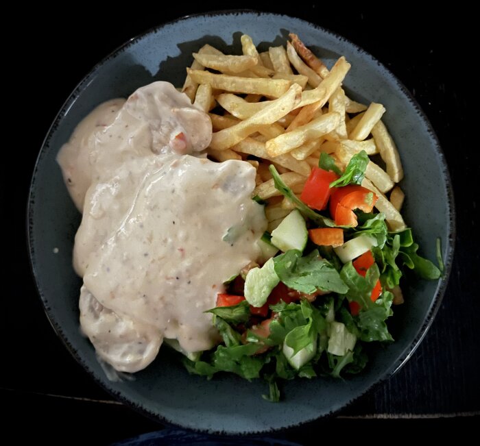 Tunna fläskkotletter med sweetchilisås, pommes frites och sallad på tallrik.