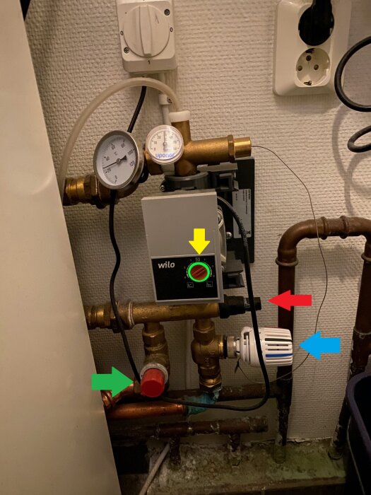 Shunt- och rörinstallationen med termostat och flera ventiler markerade med färgpilar: gul, grön, röd och blå, runt en värmepump.