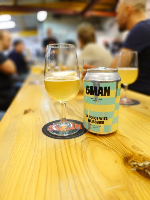 Ett glas weissbier och en burk med 5MAN La Dolce Vita Weissbier på ett bord under bryggerivisning.