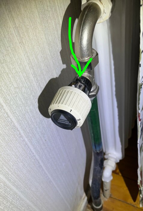 Termostatventil med insexskruv synlig, markerad med en grön pil.