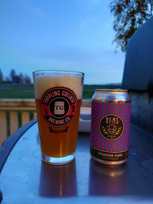 Ett glas öl och en burk Bent Water Thunder Funk IPA på ett bord utomhus.