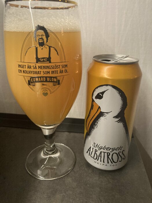 Ett glas fyllt med Stigbergets Albatross öl bredvid en öppnad burk, med etikett som visar en albatross.