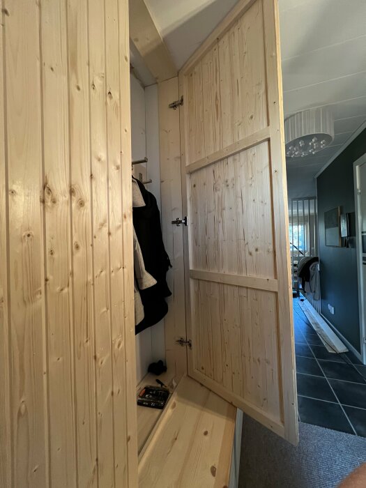 Garderobsdörrar av bastupanel som är sneda och skeva, den högra dörren glipar längst ner och den vänstra upptill. Verktyg syns på hyllan.