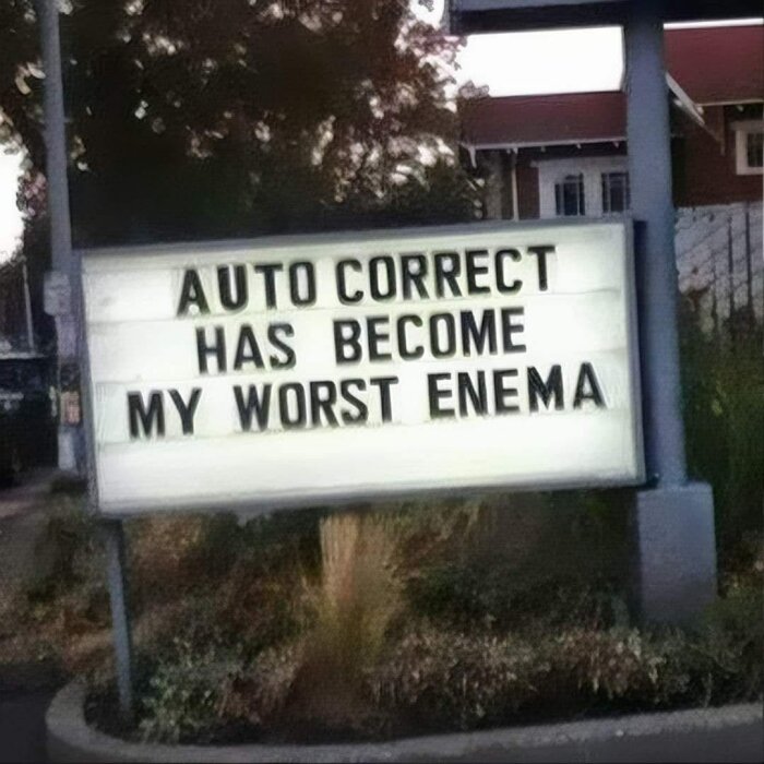 Skylt med texten "Auto correct has become my worst enema" som skämtar om stavningskontroll.