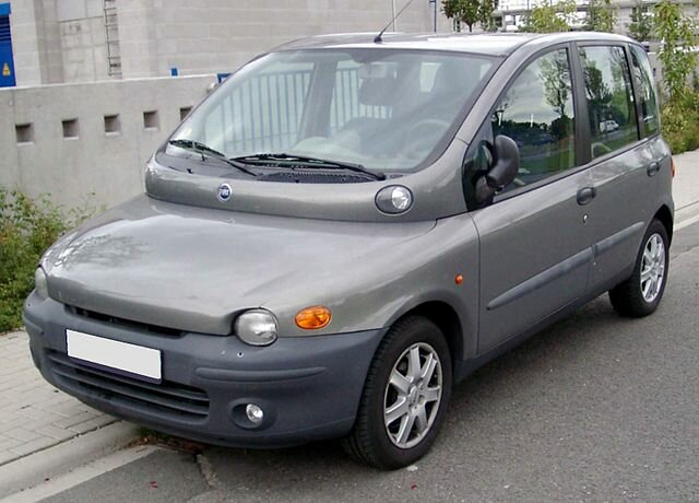 En silverfärgad Fiat Multipla parkerad vid trottoaren, känd för sin unika och praktiska design med udda form.