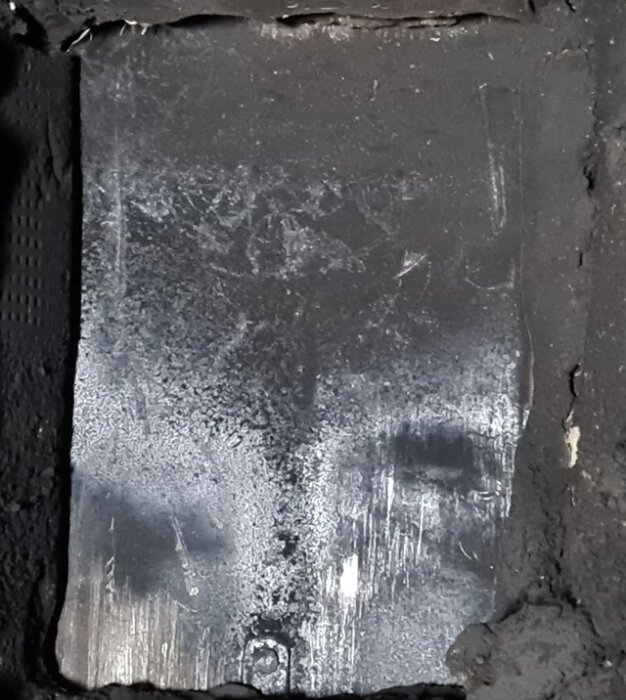 Ett sotigt metallspjäll inuti en skorsten med tecken på rost och sotavlagringar.