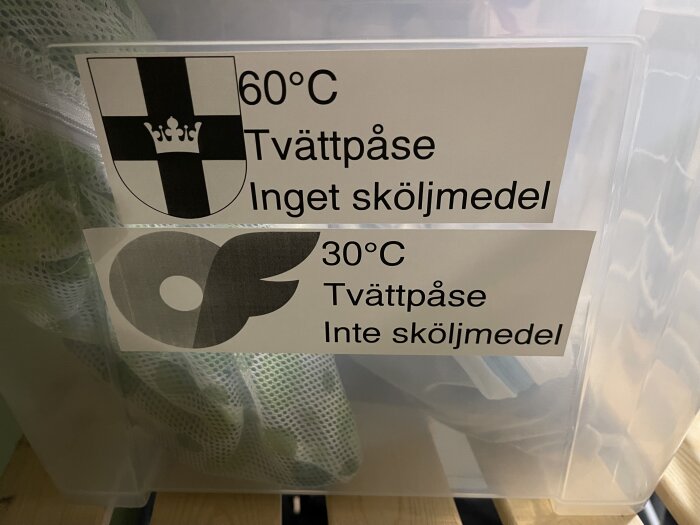 Etiketter på låda i tvättstugan med tvättråd: 60°C utan sköljmedel, 30°C utan sköljmedel, med symboler.