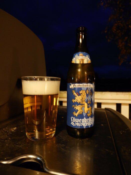 Flaska Löwenbräu München Oktoberfestbier och ett glas öl på en grill.