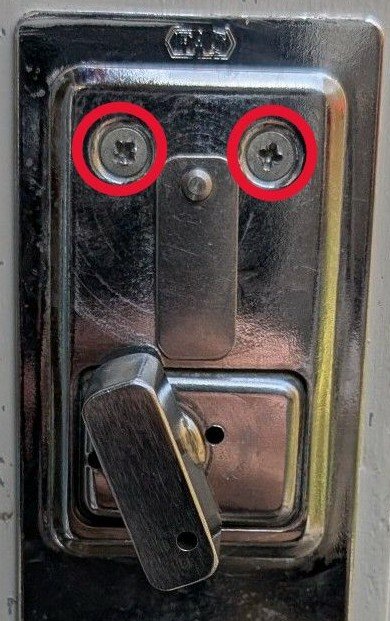 Närbild på ett låshus med två markerade skruvar för nyckelskylt, relevant för byte till Yale Doorman eller Lock Guard enligt inlägget.