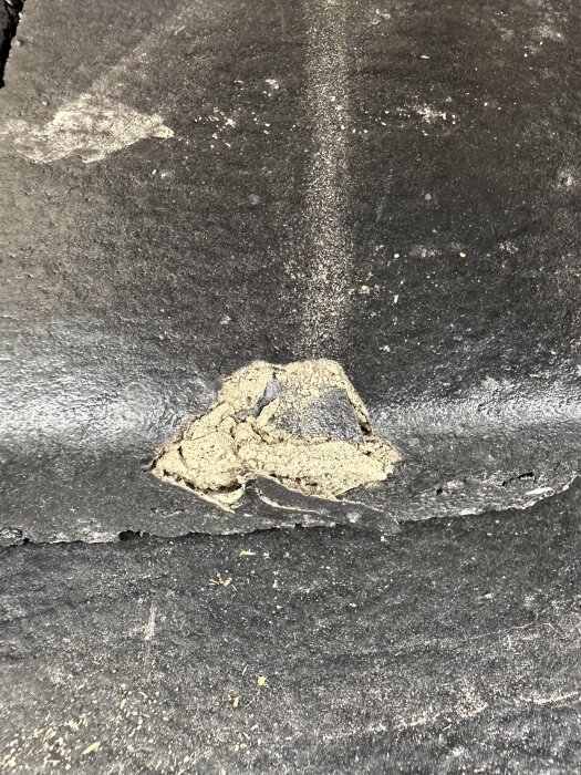 Närbild av en takpanna med ytskador där sandlagret syns, vilket tyder på fabrikationsfel.