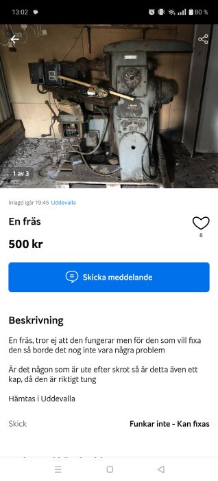 En gammal fräs med slitna delar står i ett förråd, omgiven av damm och verktyg, redo för renovering eller skrot.