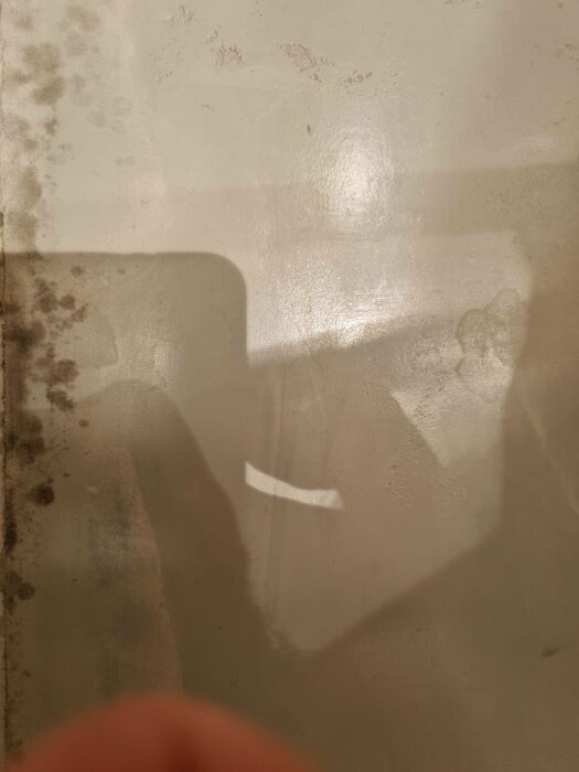 Microcementyta i badrum med mörka fläckar, eventuellt mögel, och skuggor synliga. Ytan omgjord för ett år sedan, visar känslighet för vatten och fukt.