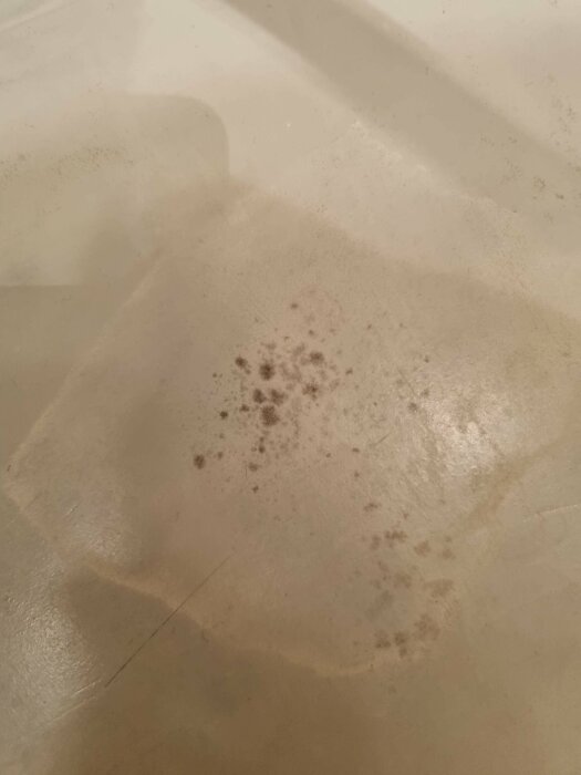 Närbild på badrumsgolv med microcement som visar mörka fläckar som kan vara mögel, fastän ytskiktet är nygjort och god ventilation finns.